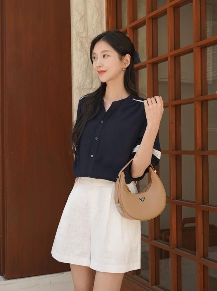 Sơ mi màu tối đơn điệu sẽ trở nên duyên dáng, ngọt ngào hơn khi mix cùng quần shor trắng. Set đồ này nền nã nhưng không kém phần thời trang, gợi cảm khi bạn chọn kiểu quần short ngắn giúp khoe chân thon.