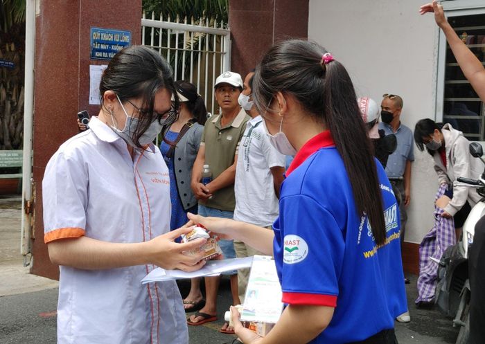 Các thí sinh nhận bánh, nước suối... sau khi bước ra khỏi phòng thi từ các sinh viên tình nguyện.