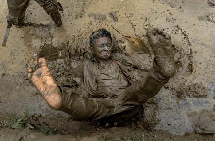 Một cậu bé nghịch bùn trên cánh đồng trong Ngày lúa quốc gia ở Bahunbesi. [Ảnh AP]