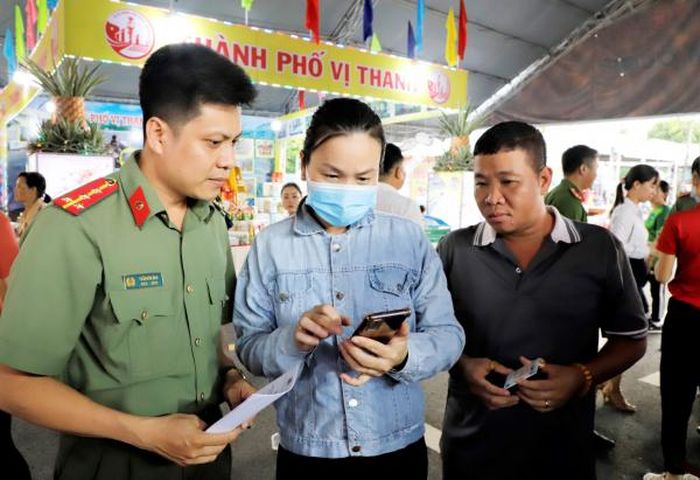 Người dân tham gia hội chợ được CBCS Công an tỉnh Hậu Giang tuyên truyền về lợi ích khi sử dụng tài khoản định danh điện tử trên ứng dụng VNeID.