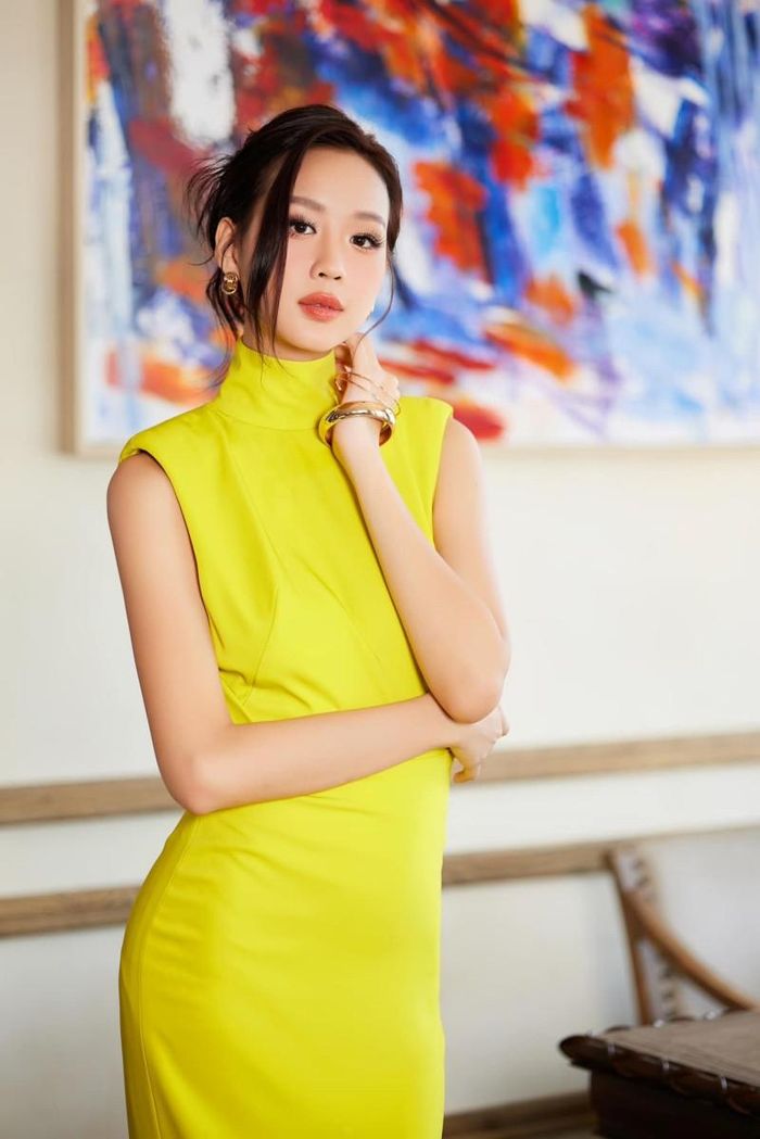 Bảo Ngọc kiêu kỳ tạo dáng với chiếc váy cổ cao màu vàng chanh bắt mắt - thiết kế mang kiểu dáng bút chì, vai vuông giúp tôn lên chiều cao nổi bật của nàng hậu. Cô để tóc mái lơi đằm thắm và phối cùng phụ kiện màu gold.