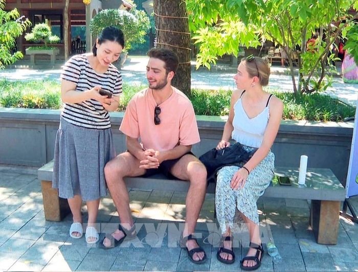 Cán bộ Trung tâm thông tin xúc tiến du lịch, Sở Du lịch tỉnh Ninh Bình hướng dẫn du khách tại Khu du lịch sinh thái Tràng An cài đặt phần mềm du lịch thông minh. Ảnh: Thùy Dung - TTXVN
