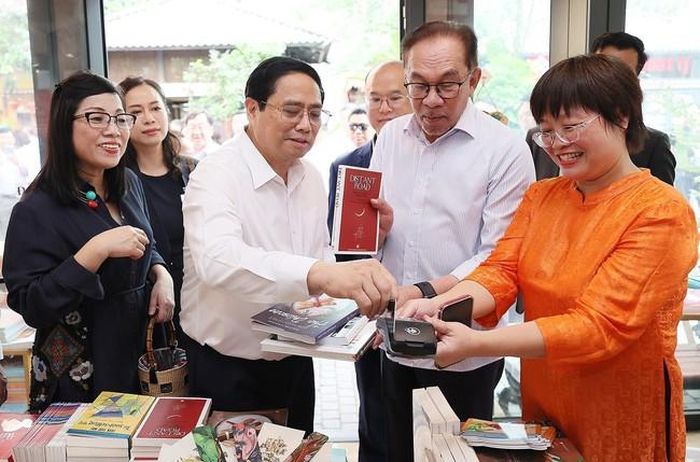 Thủ tướng Phạm Minh Chính mua sách tặng Thủ tướng Malaysia Anwar Ibrahim và Phu nhân. Ảnh: Dương Giang-TTXVN
