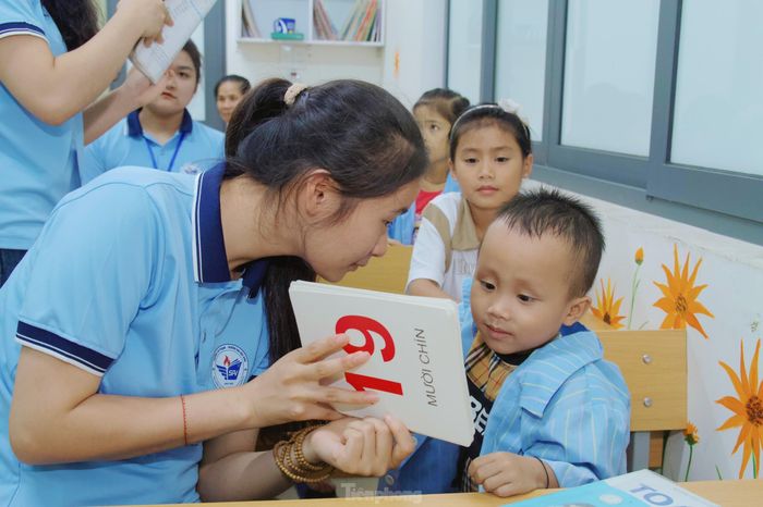 Tỉ mỉ chỉ cho một bé trai tập viết, bạn Lương Thị Nhược Hằng (SN 2003, lớp 62A4 Giáo dục tiểu học, Trường Đại học Vinh) cho biết, thành viên của lớp học không cố định, có khoảng gần 20 em với độ tuổi dao động từ khoảng 4 -10 tuổi và không cố định vì nhiều lý do.