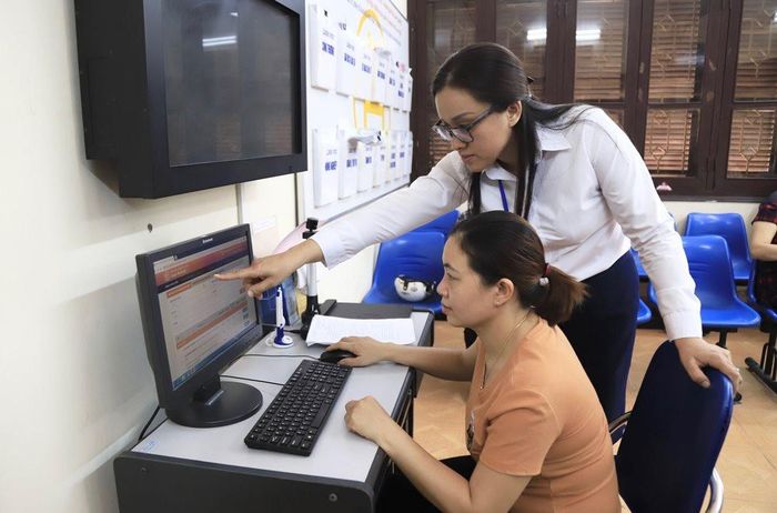 Hỗ trợ người dân giải quyết dịch vụ công trực tuyến tại bộ phận “một cửa” huyện Thanh Trì. Ảnh: Quang Thái