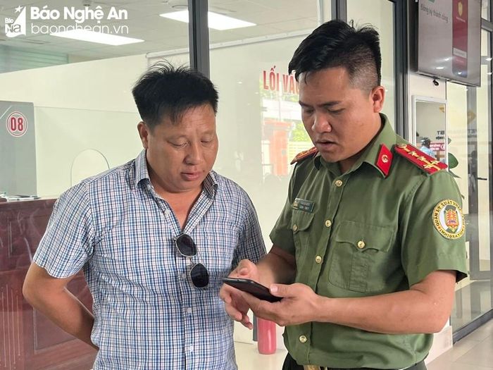 Cán bộ Phòng Quản lý xuất, nhập cảnh hướng dẫn đăng ký, kích hoạt tài khoản định danh điện tử ngay tại trụ sở đơn vị cho công dân đến làm các thủ tục liên quan đến lĩnh vực xuất nhập cảnh. Ảnh: PV