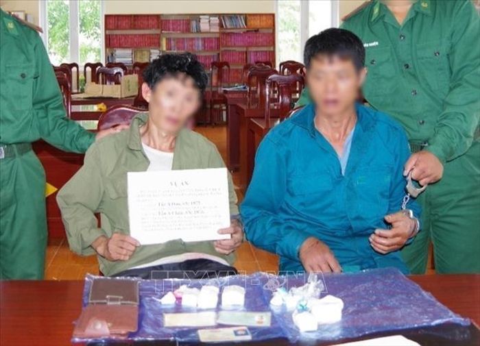 Hai đối tượng Tẩn A Dao (bên trái ảnh) và Tẩn A Chản cùng tang vật vụ án bị bắt giữ tại cơ quan điều tra. Ảnh: TTXVN phát