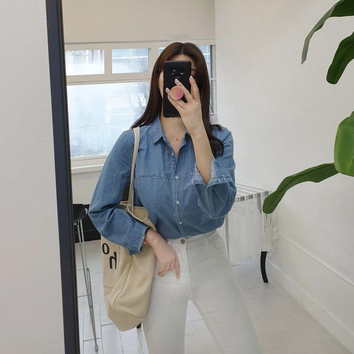 Cô nàng này chọn mix sơ mi denim với quần jeans trắng, tông màu xanh - trắng là bộ đôi cơ bản, giúp người mặc trông trẻ trung hơn đáng kể. Cô không quên sơ vin hack dáng và mang thêm túi tote năng động
