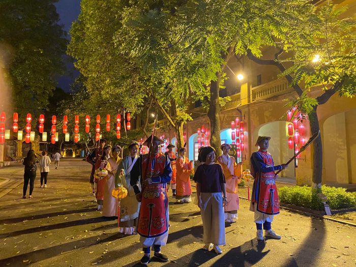 Du khách chụp ảnh lưu niệm cùng đoàn lính canh, cung nữ trong tour du lịch đêm Giải mã Hoàng thành Thăng Long (Hà Nội).