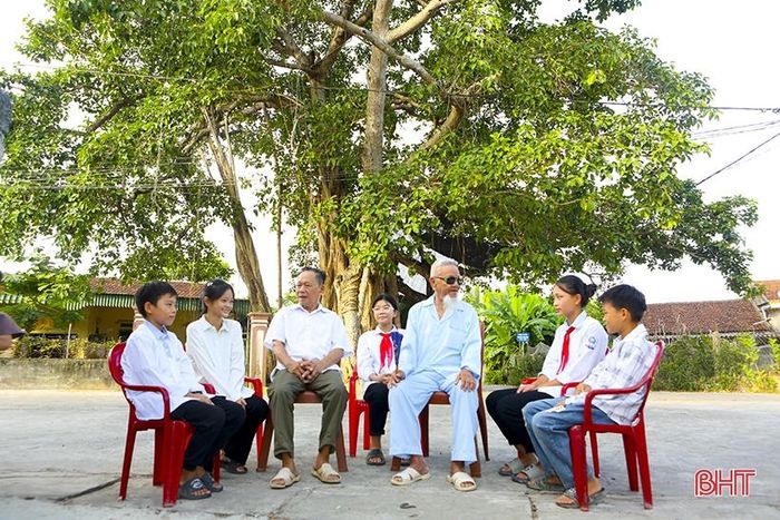 Các em học sinh Trường THCS Hồng Tân nghe đảng viên cao tuổi thôn Trung Sơn (Hồng Lộc) kể chuyện về lịch sử đấu tranh cách mạng trên quê hương tại cây đa Giếng Chua.