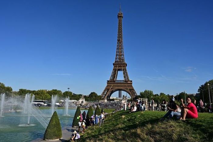 Khách du lịch tránh nóng tại vườn Trocadéro bên cạnh Tháp Eiffel ở Paris, Pháp, ngày 21/8/2023. Ảnh: AFP/TTXVN