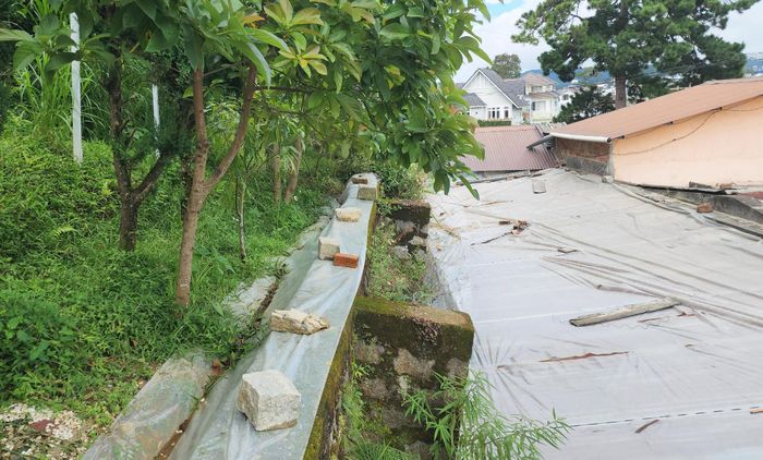 Người dân phủ bạt ngăn nước mưa tại những chỗ bị lún, nứt