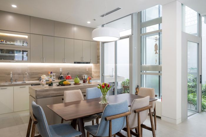 Một khoảng lùi vừa đủ từ góc hẻm được thiết kế để dành chỗ cho lối vào và khoảng sân giản dị trước nhà. Bậc tam cấp bằng đá granite được tạo hình uốn cong hướng ra sân và hệ cửa kính lớn cong lõm vào trong tạo ra một khoảng hiên nhà hình elip độc đáo ở tầng trệt.