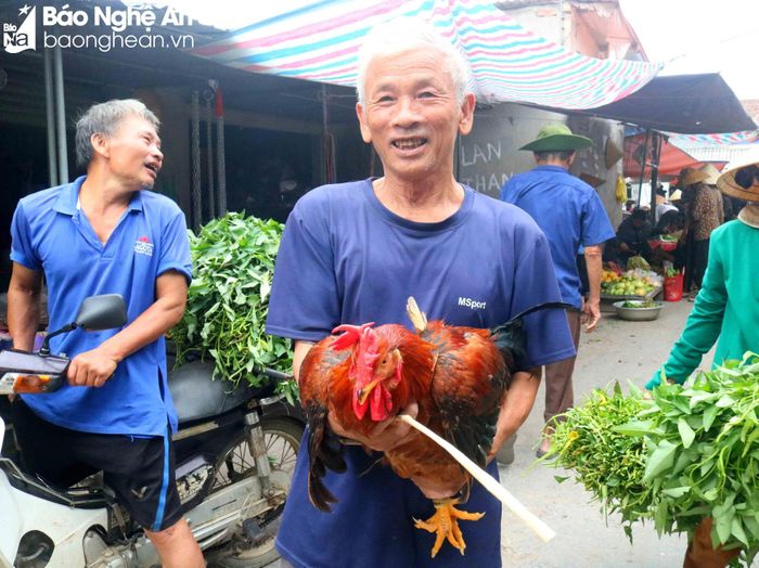  Một cụ ông đi chợ Cồn xã Thanh Dương (Thanh Chương) phấn khởi khi mua được 1 con gà trống về làm cỗ cúng Rằm. Ảnh: Huy Thư 