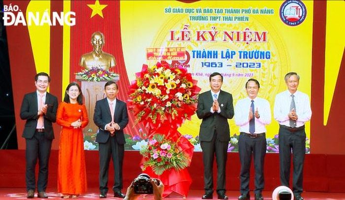 Chủ tịch UBND thành phố Lê Trung Chinh (thứ 3 từ phải sang) cùng lãnh đạo thành phố tặng hoa chúc mừng nhà trường. Ảnh: NGỌC HÀ