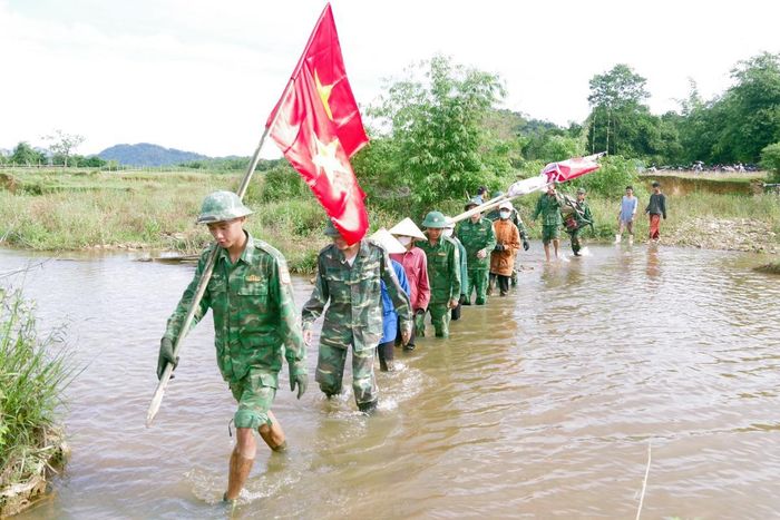 Cán bộ, chiến sĩ và đoàn viên thanh niên vượt suối giúp người dân thu hoạch lúa. Ảnh: Võ Tiến