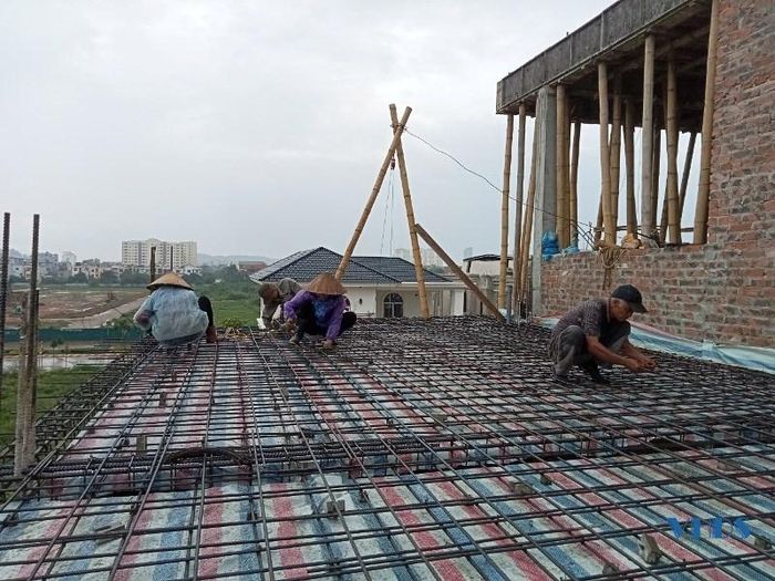 Thợ sắt mặc áo mưa để buộc dầm sàn, trong đó có những người phụ nữ đã lớn tuổi.