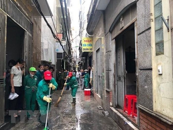 Lực lượng chức năng quận Thanh Xuân dọn dẹp vệ sinh trước chung cư mi ni xảy ra vụ cháy khiến nhiều người thương vong trên phố Khương Hạ. (Ảnh: TTXVN phát)