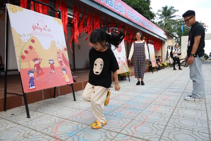 Một em nhỏ chơi nhảy lò cò trong không gian trò chơi dân gian ở Bảo tàng tỉnh.