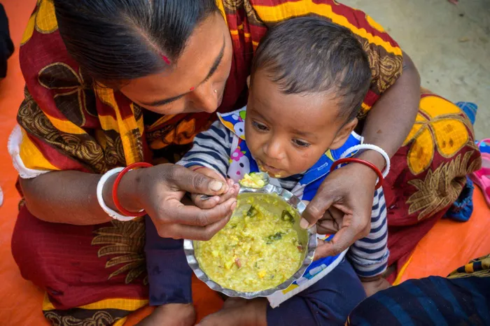 Bà mẹ cho con ăn cháo tại làng Tildanga (Bangladesh), nơi 27% trẻ dưới 5 tuổi bị còi cọc. Ảnh: World Vision.