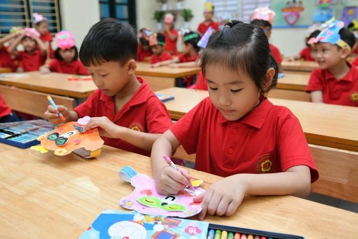Các bạn học sinh lớp 1 tự tay tô màu cho những chiếc mũ đội bằng giấy.