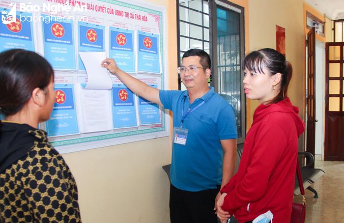 Cán bộ Văn phòng UBND thị xã Thái Hòa hướng dẫn người dân tìm hiểu các thủ tục hành chính tại bộ phận "một cửa". Ảnh: MH