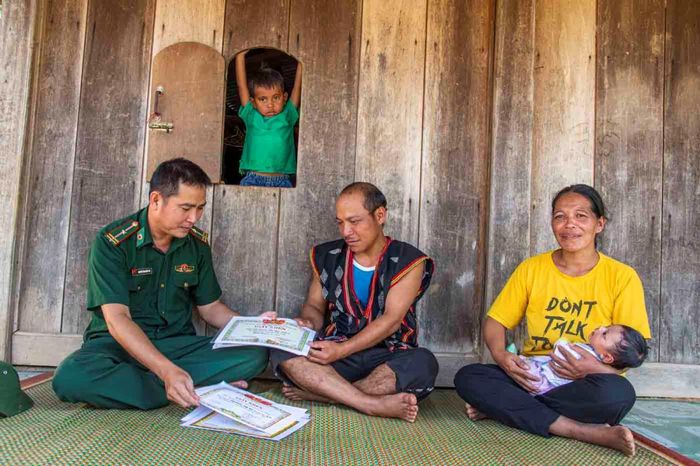Chị Zơ Rum Thị Brai và chồng tâm sự với Thiếu tá, bác sĩ Nguyễn Văn Quốc Trí về những đứa con được sinh tại trạm xá đã trưởng thành, học tập tốt. Ảnh: Văn Chương