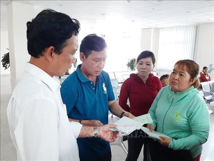 Cán bộ Bảo hiểm xã hội tỉnh Long An (bìa trái) hướng dẫn người dân các thủ tục hành chính. Ảnh tư liệu: Đức Hạnh/TTXVN