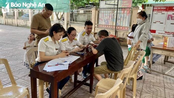  Cán bộ cục Thuế Nghệ An hướng dẫn người dân TP. Vinh cài đặt ứng dụng Thuế điện tử eTax Mobile trên thiết bị di động. Ảnh: C.T.V 