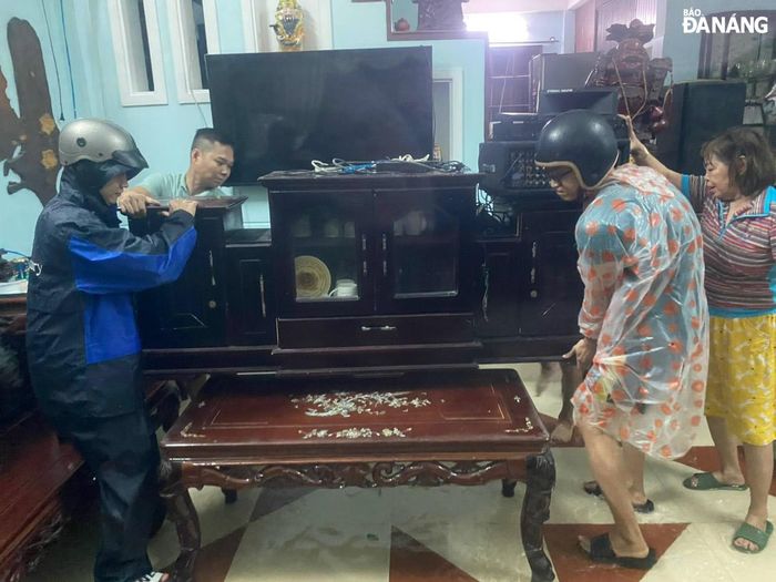 Các lực lượng giúp nhân dân phường Hòa Khánh Nam kệ dồ đạc, tránh hư hỏng do mưa lũ gây ra. (ảnh chụp tối 13-10). Ảnh: H.T