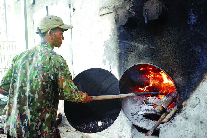 Nhân công đốt lửa cháy để sấy cau. 