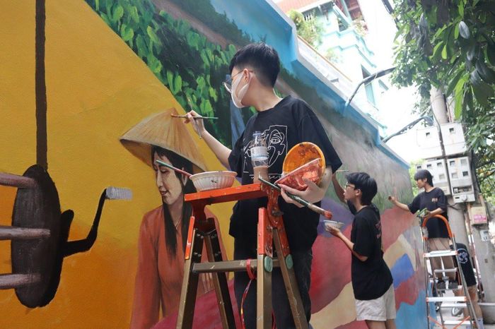 Thành viên nhóm vẽ Mộc đang hoàn thiện bích họa tái hiện quy trình sản xuất lụa của làng.