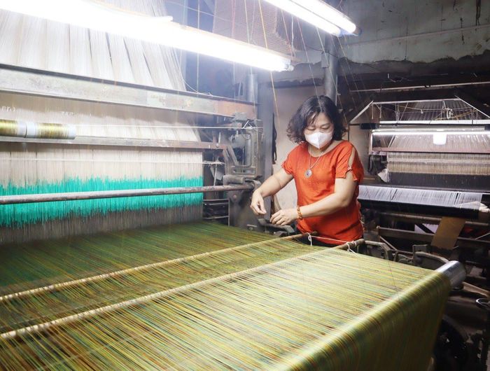 Nghệ nhân dệt lụa Trần Thị Ngọc Lan ở làng Vạn Phúc bên khung dệt.