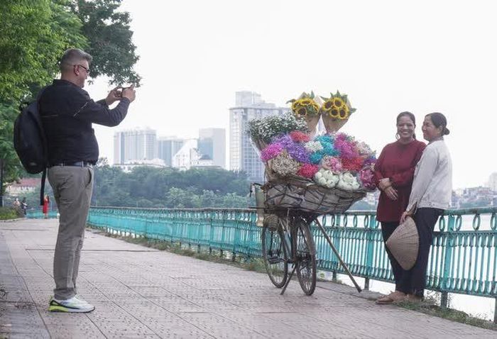 Hai người khách Tây không mua hoa, mà chỉ nhờ bà Nhung đứng cạnh làm nền chụp ảnh