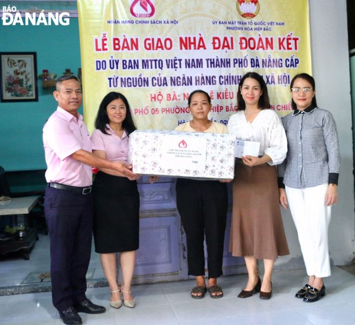 Phó Chủ tịch Ủy Ban MTTQ Việt Nam thành phố Trần Thị Mẫn (bìa phải) cùng đại diện lãnh đạo Ủy Ban MTTQ Việt Nam quận Liên Chiểu và Ngân hàng Chính sách xã hội thành phố tặng quà đến gia đình bà Ngô Lê Kiều Linh tại buổi bàn giao nhà Đại đoàn kết. Ảnh: T.PHƯƠNG