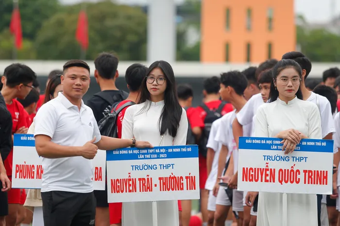 Nữ sinh đại diện cầm biển trường THPT Nguyễn Trãi - Thường Tín cùng huấn luyện viên đội bóng của trường