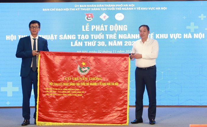 Phó Chủ tịch Thường trực UBND TP Hà Nội, Trưởng ban Chỉ đạo Hội thi Lê Hồng Sơn (bên phải) trao cờ truyền thống Hội thao kỹ thuật sáng tạo tuổi trẻ ngành Y tế khu vực Hà Nội lần thứ 30, năm 2023 cho lãnh đạo Bệnh viện Thanh Nhàn. Ảnh: Bảo Anh