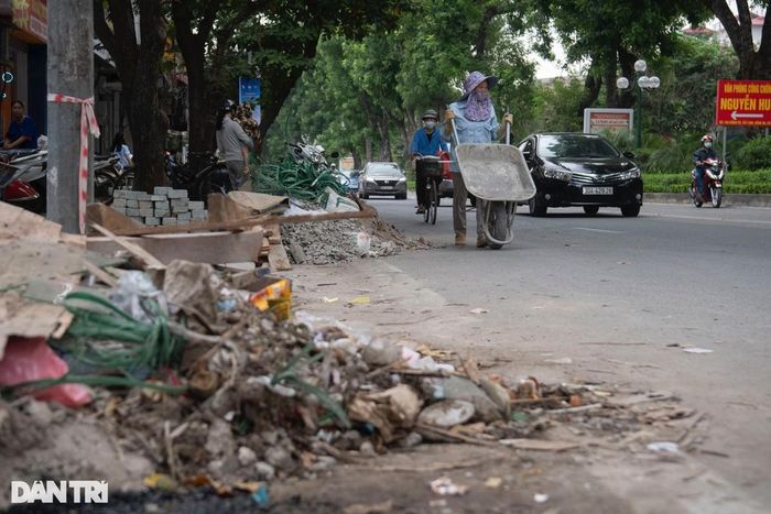 Anh Nguyễn Minh Huy cùng nhân viên đang trải những tấm bìa carton ra trước khu vực quán ăn của mình trên mặt phố Hào Nam để khách ra vào cho tiện và tránh bụi bặm bùn đất bị kéo theo vào quán.