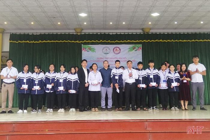 Anh Phan Trọng Hải (giữa) cùng những người bạn và Ban Giám hiệu Trường THPT Nguyễn Văn Trỗi trao học bổng cho các em học sinh nghèo học giỏi, dịp tháng 2/2023.