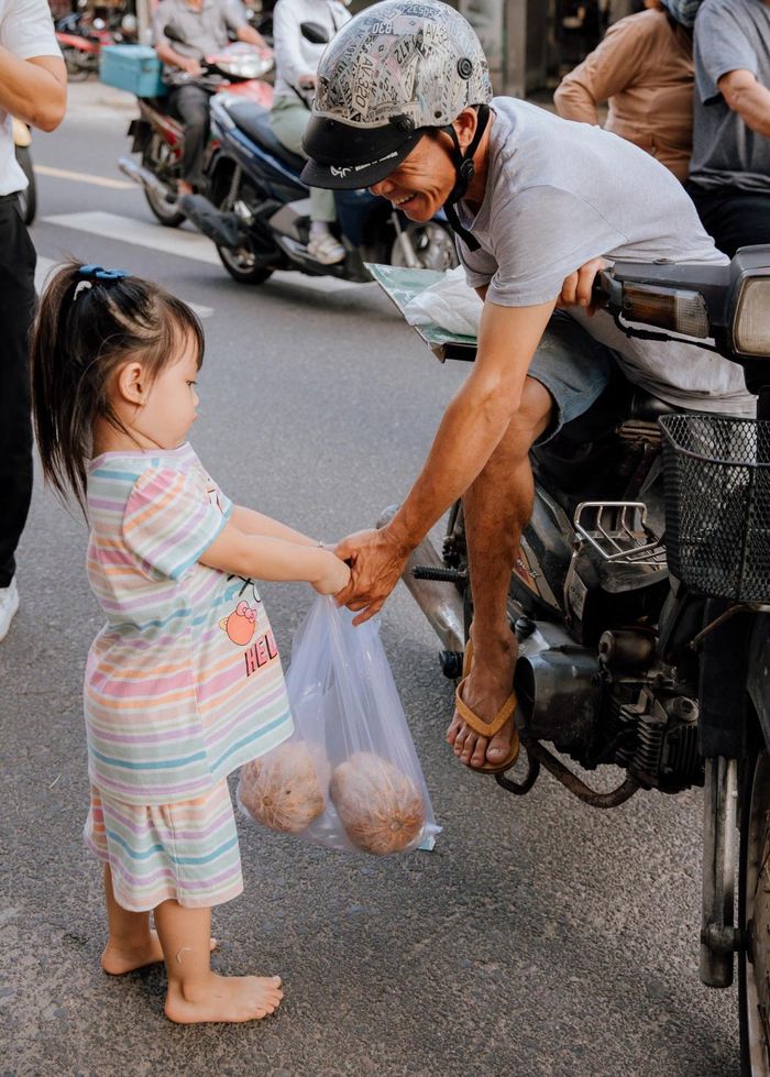 Một em bé tại Nha Trang trao bí đỏ miễn phí cho người dân.