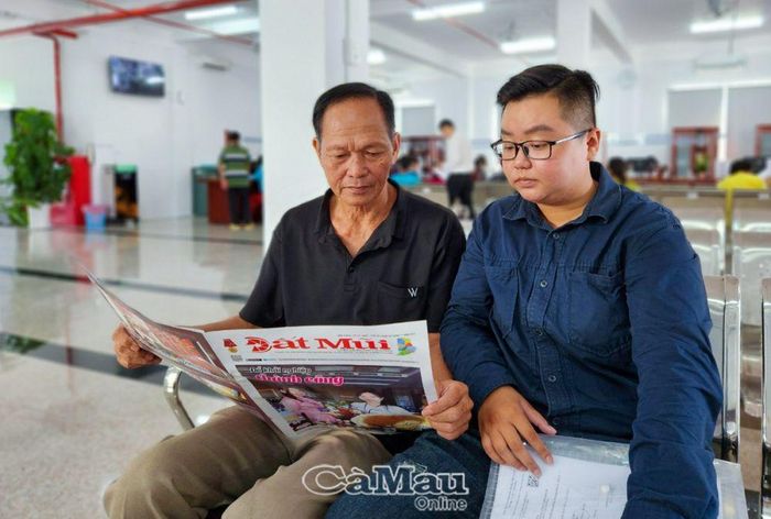 Người dân tranh thủ đọc báo trong thời gian chờ giải quyết thủ tục hành chính. (Ảnh chụp tại Trung tâm Giải quyết thủ tục hành chính TP Cà Mau).