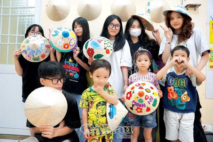 Các bạn nhỏ khoe thành phẩm của mình sau buổi workshop vẽ trên nón lá.