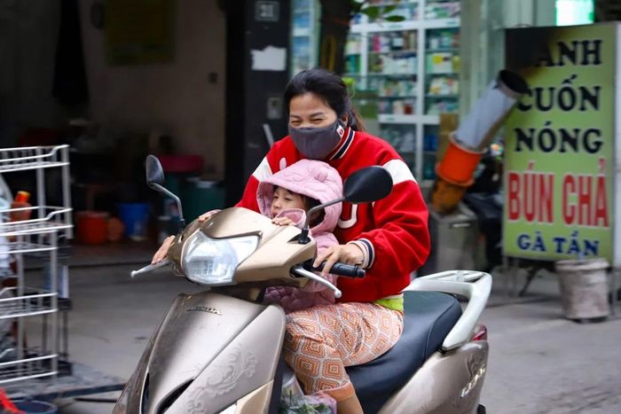 Người dân chật vật di chuyển trong thời tiết lạnh kèm gió lớn. (Ảnh: Hoài Nam/Vietnam+)