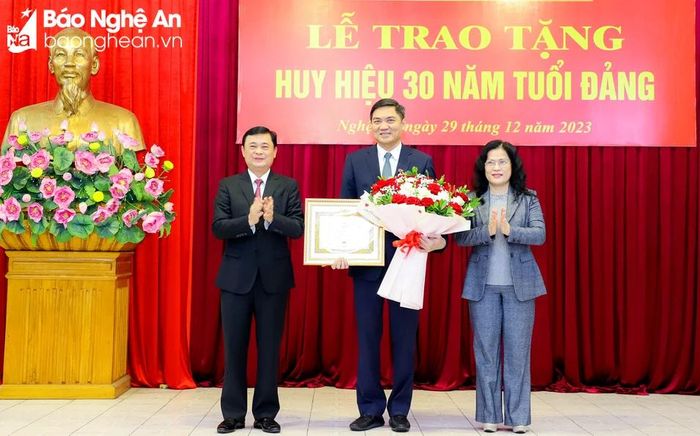 Đồng chí Thái Thanh Quý - Ủy viên Ban Chấp hành Trung ương Đảng, Bí thư Tỉnh ủy, Chủ tịch HĐND tỉnh, Trưởng Đoàn ĐBQH tỉnh trao Huy hiệu 30 năm tuổi Đảng; đồng chí Nguyễn Thị Kim Chi - Bí thư Đảng ủy Khối Các cơ quan tỉnh tặng hoa chúc mừng đồng chí Hoàng Nghĩa Hiếu. Ảnh: Phạm Bằng