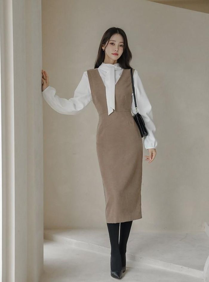 Mẫu váy yếm dày dặn, tối giản và có phần kín đáo sẽ thêm phần tươi tắn, điệu đà khi kết hợp thêm áo blouse trắng có phần cổ cách điệu.