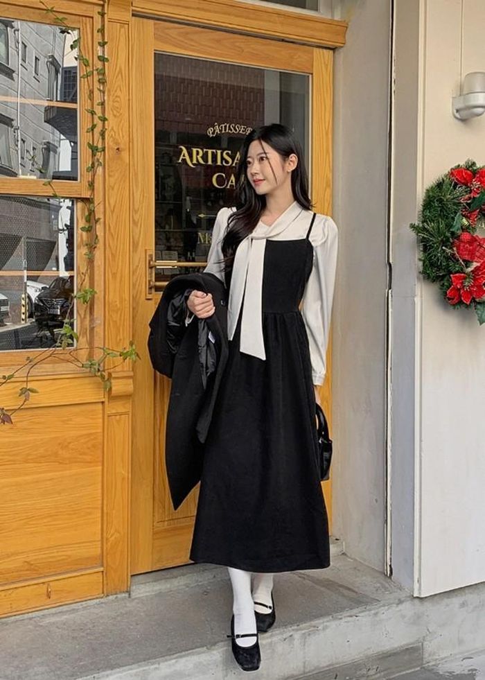 Váy dây màu đen mix áo blouse trắng giúp bạn gái trông tươi tắn và “hack tuổi”. Set đồ trẻ trung nhưng vẫn đảm bảo nét kín đáo, nền nã, có thể diện cả đi làm lẫn đi chơi, đi học.