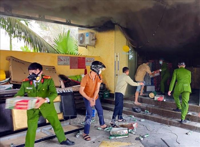 Lực lượng chức năng hỗ trợ vận chuyển hàng hóa trong quán ra ngoài khi vụ cháy xảy ra. Ảnh: TTXVN phát