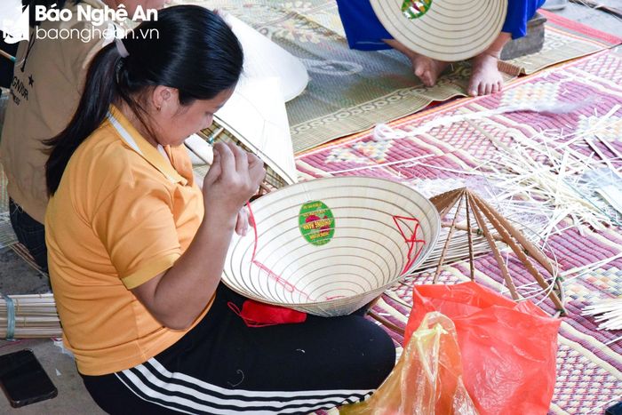  Khâu cuối cùng là làm quai nón. Những sợi chỉ màu được luồn khéo léo vào hai bên vành nón để móc quai nón. Ảnh: Hoài Thu 