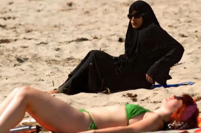 Phụ nữ địa phương mặc Burkha khi đi biển cùng một phụ nữ phương Tây