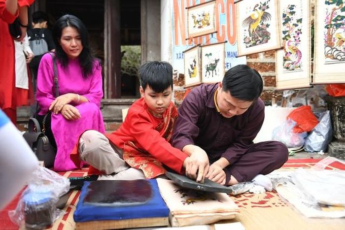 Nghệ nhân làng tranh Đông Hồ hướng dẫn các du khách nhí công đoạn làm tranh